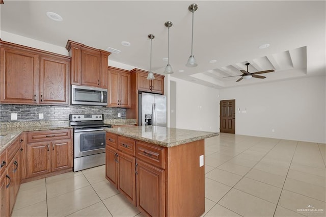 kitchen featuring pendant lighting, appliances with stainless steel finishes, a center island, and light stone countertops