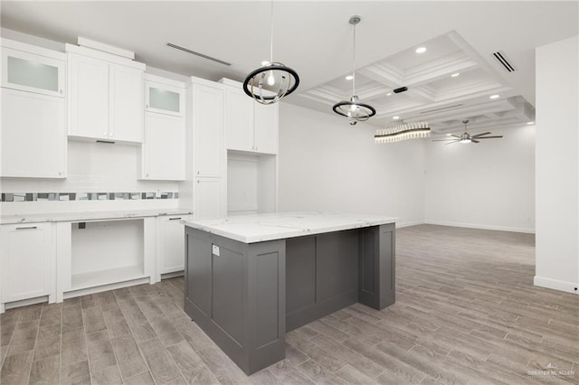 kitchen featuring ceiling fan, a kitchen island, coffered ceiling, white cabinets, and light stone counters