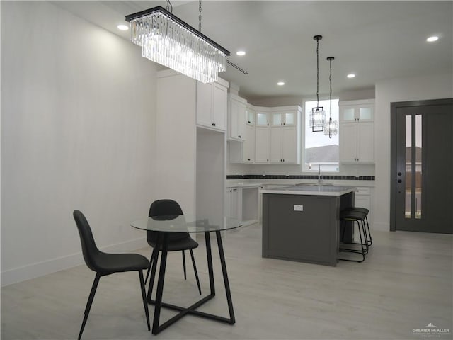 3309 S Marla Ct, Edinburg, TX 78542 - kitchen with white cabinets, a notable chandelier, light wood finished floors, baseboards, and a center island with sink