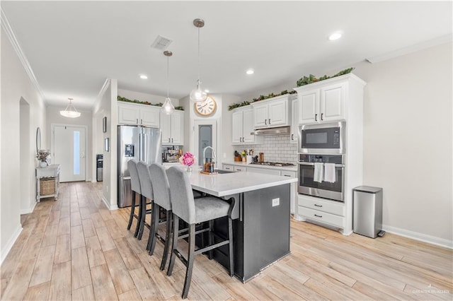 kitchen featuring a sink, visible vents, backsplash, crown molding, and appliances with stainless steel finishes