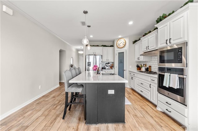 kitchen with tasteful backsplash, white cabinetry, hanging light fixtures, and stainless steel appliances