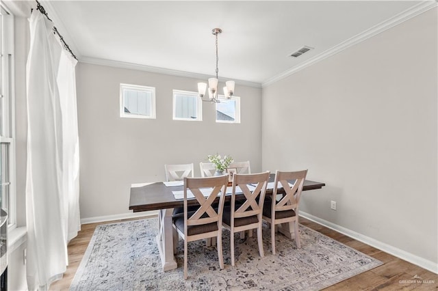 dining space with light wood finished floors, visible vents, crown molding, baseboards, and a notable chandelier