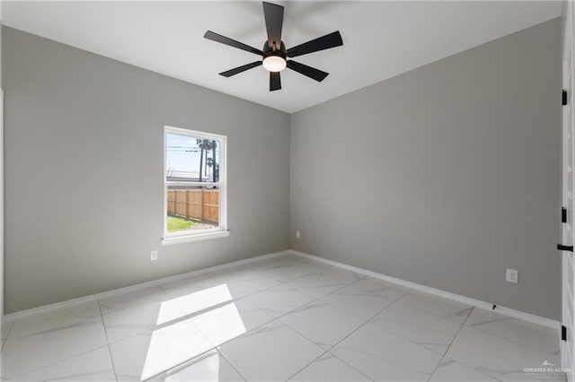 empty room with baseboards, a ceiling fan, and marble finish floor