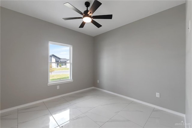 empty room with marble finish floor, baseboards, and a ceiling fan
