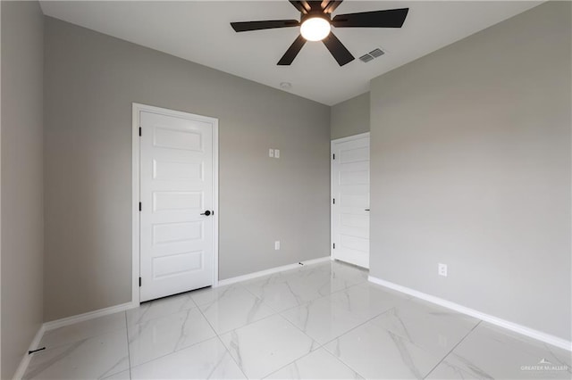empty room with marble finish floor, ceiling fan, baseboards, and visible vents
