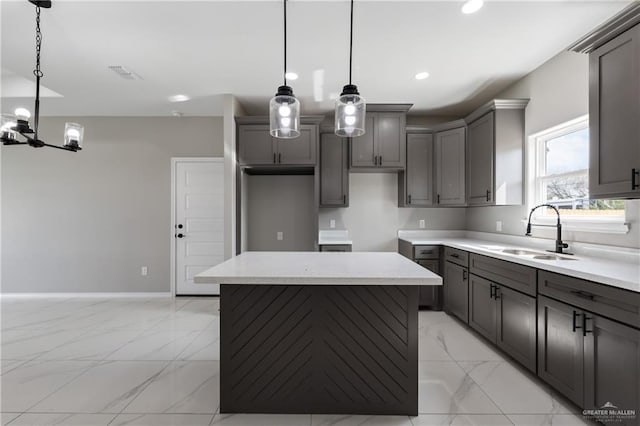 kitchen featuring a center island, a sink, visible vents, gray cabinetry, and marble finish floor
