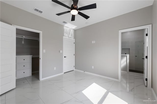 unfurnished bedroom with marble finish floor, a spacious closet, baseboards, and visible vents