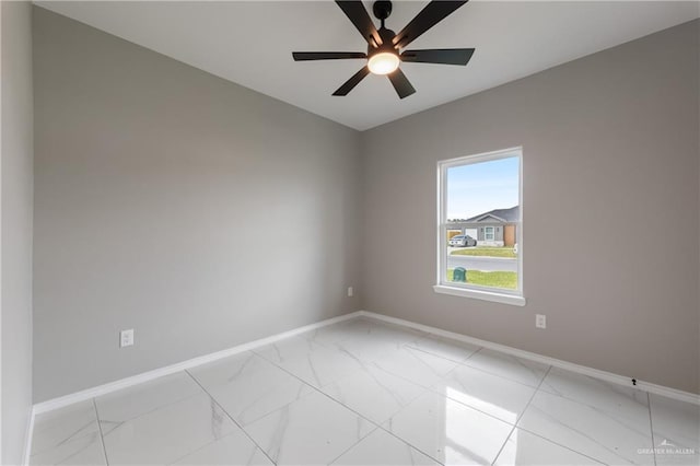 empty room with baseboards, a ceiling fan, and marble finish floor