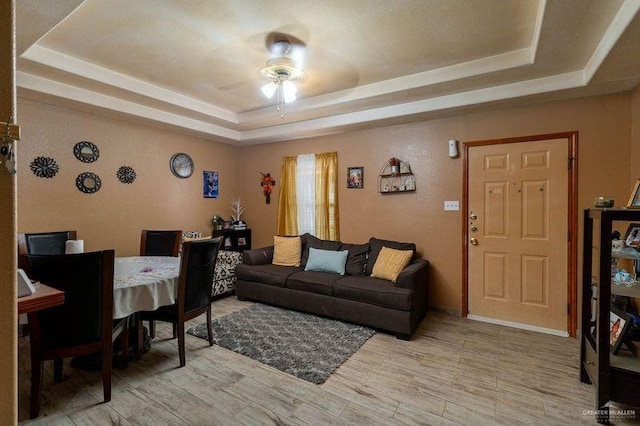 living room featuring ceiling fan and a tray ceiling