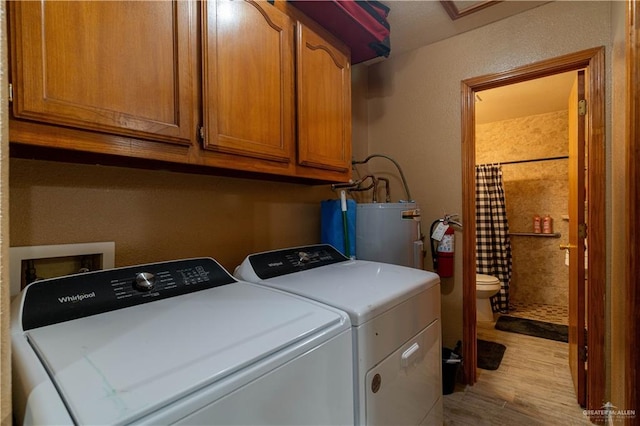 laundry room featuring cabinets, washing machine and clothes dryer, light hardwood / wood-style flooring, and water heater