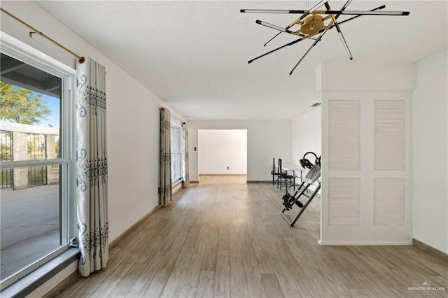 hall with an inviting chandelier and light hardwood / wood-style flooring