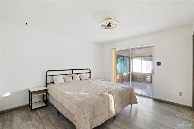 bedroom with hardwood / wood-style floors, a textured ceiling, and access to outside