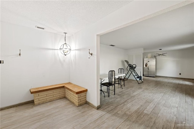 dining area featuring wood-type flooring, a textured ceiling, and an inviting chandelier