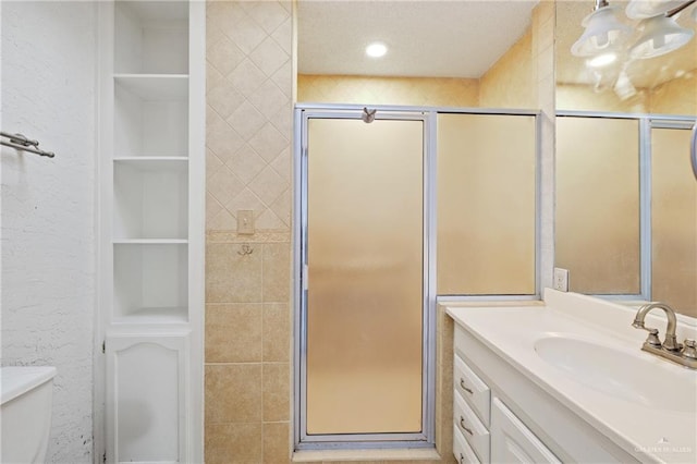 bathroom with vanity, toilet, a shower with shower door, and built in shelves