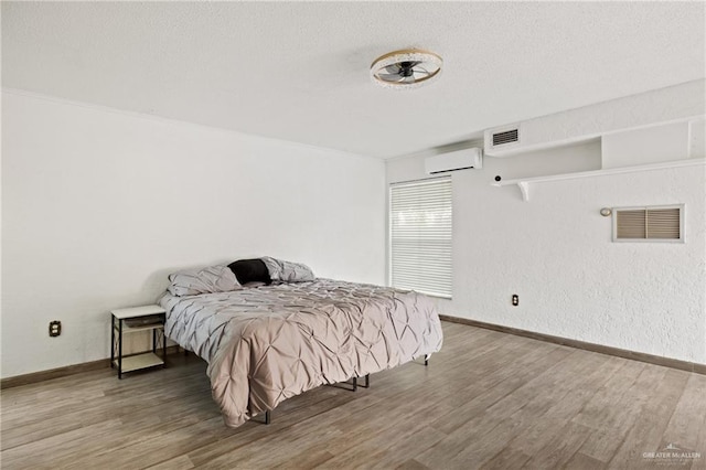 bedroom featuring wood-type flooring and a wall unit AC