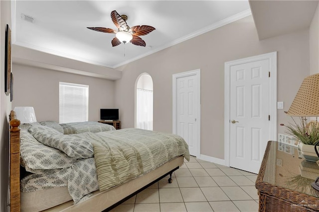 tiled bedroom with two closets, ceiling fan, and crown molding