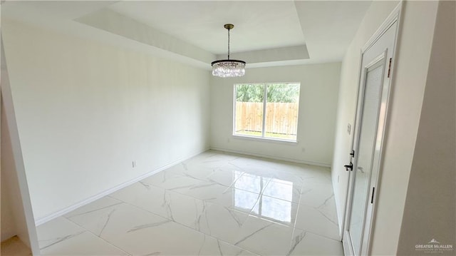 empty room with a tray ceiling and an inviting chandelier