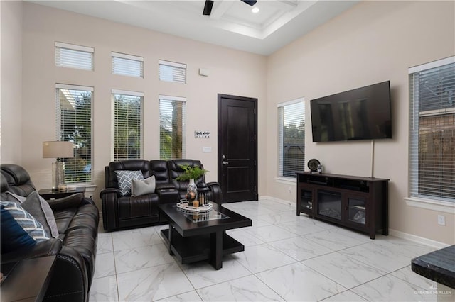 living room with ceiling fan, a healthy amount of sunlight, and a high ceiling