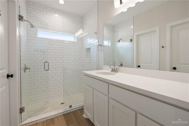 bathroom featuring wood-type flooring, an enclosed shower, and vanity