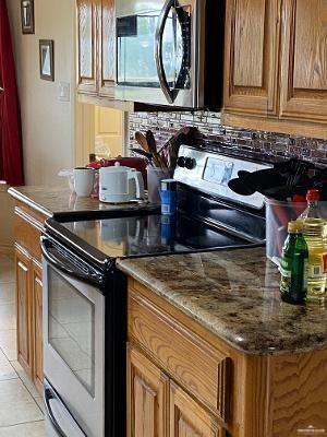 kitchen featuring appliances with stainless steel finishes, stone countertops, and light tile patterned flooring