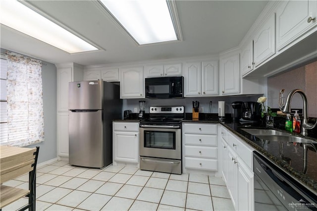 104 E Parade Dr Unit 12, South Padre Island, TX 78597 - kitchen featuring dark stone counters, sink, black appliances, light tile patterned floors, and white cabinetry