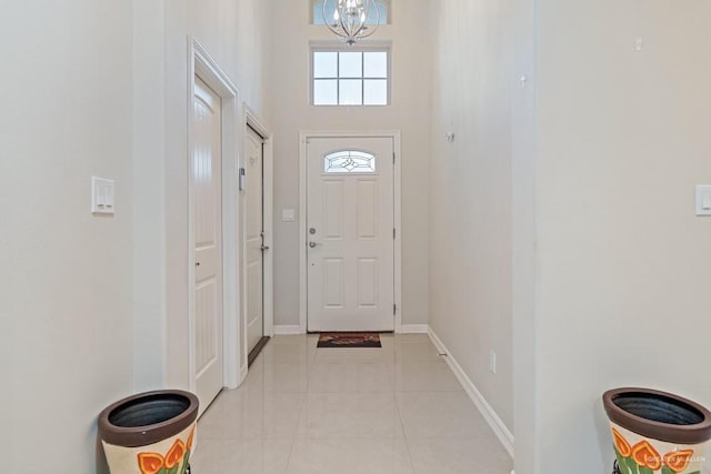 doorway with light tile patterned floors, a high ceiling, and an inviting chandelier