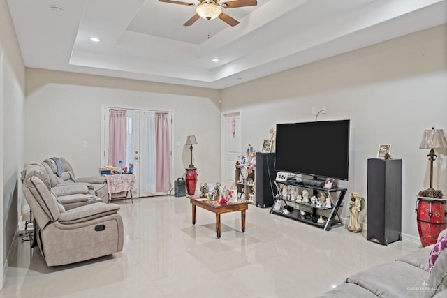 living room featuring a tray ceiling and ceiling fan