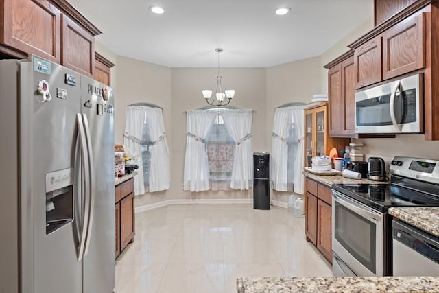 kitchen with an inviting chandelier, light stone counters, pendant lighting, light tile patterned flooring, and appliances with stainless steel finishes