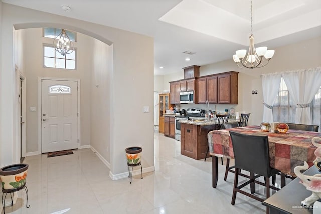 interior space featuring light stone countertops, a wealth of natural light, stainless steel appliances, pendant lighting, and a chandelier