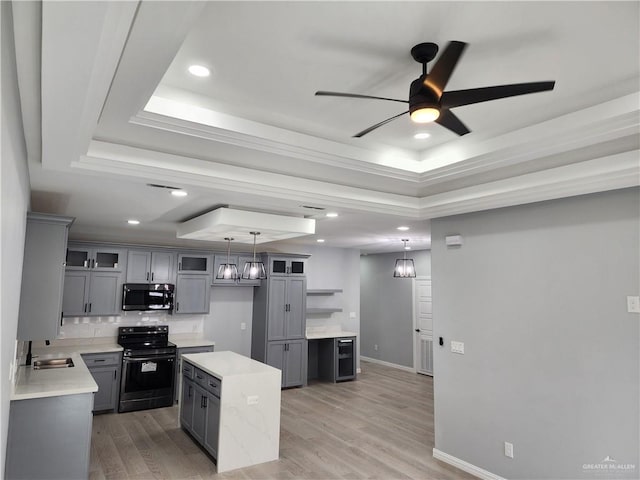 2838 Allen Dr, Edinburg, TX 78539 - kitchen with black / electric stove, a tray ceiling, gray cabinets, ceiling fan, and a center island