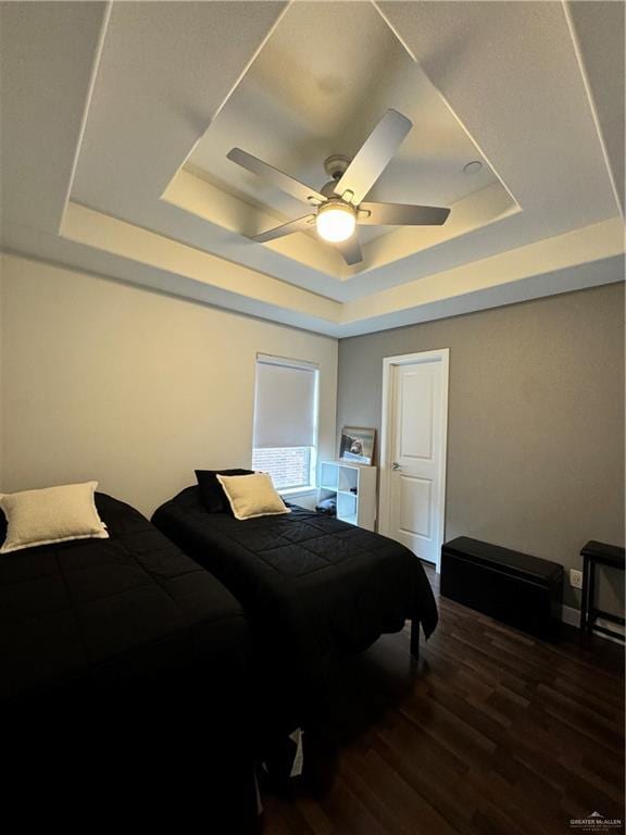 bedroom with ceiling fan, dark hardwood / wood-style floors, and a raised ceiling