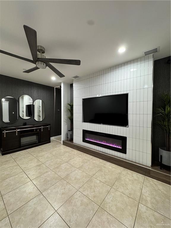 unfurnished living room with light tile patterned floors, a large fireplace, and ceiling fan