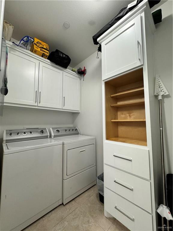 laundry room featuring cabinets, light tile patterned flooring, and separate washer and dryer