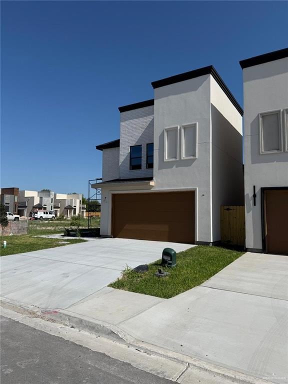 contemporary home with stucco siding, driveway, a residential view, and a garage