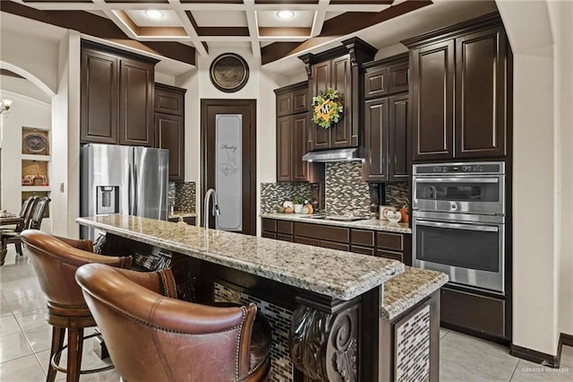 kitchen featuring stainless steel appliances, coffered ceiling, beamed ceiling, a breakfast bar, and a kitchen island