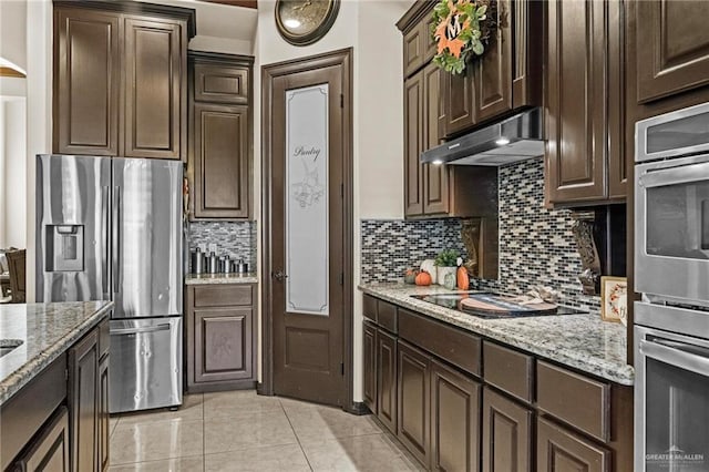 kitchen featuring backsplash, light tile patterned floors, light stone counters, dark brown cabinetry, and stainless steel appliances