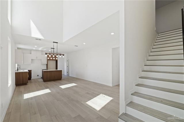 2312 Corales St, Mission, TX 78573 - unfurnished living room with a towering ceiling, stairway, light wood-style flooring, recessed lighting, and a sink