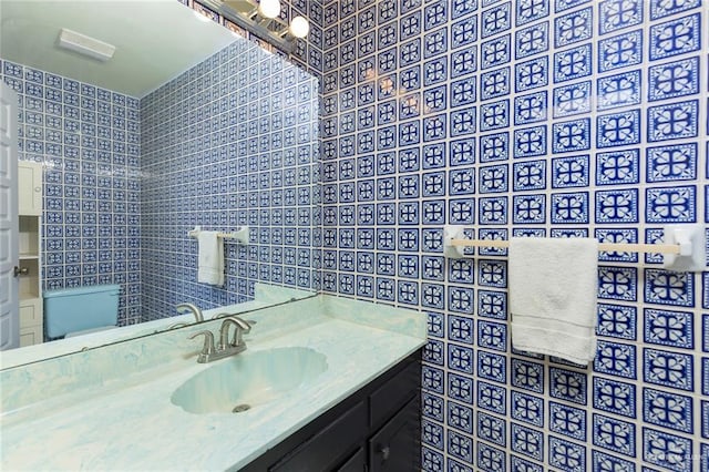 bathroom featuring vanity, tile walls, and toilet