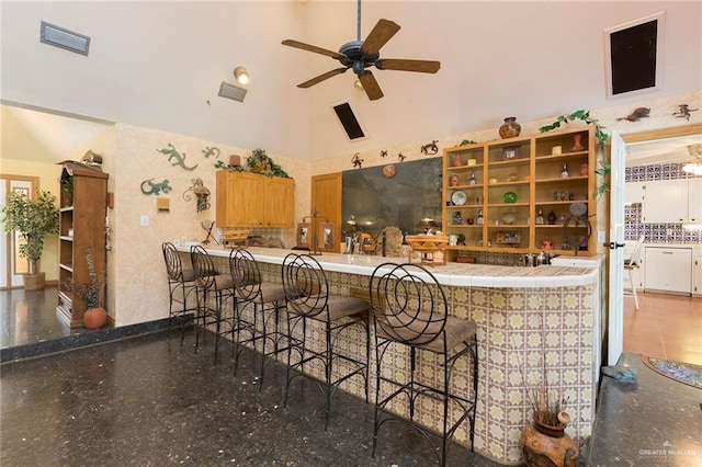 exterior space with ceiling fan, tile countertops, and high vaulted ceiling