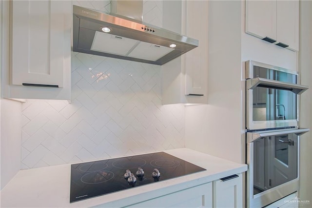 kitchen with exhaust hood, light countertops, decorative backsplash, double oven, and black electric cooktop