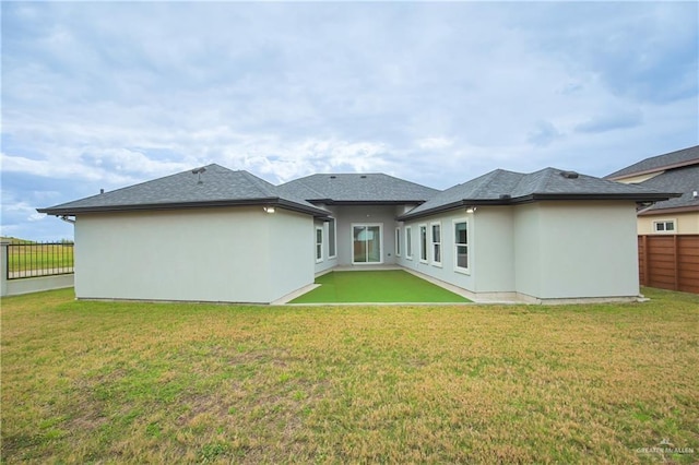 back of house with a lawn, fence, and stucco siding