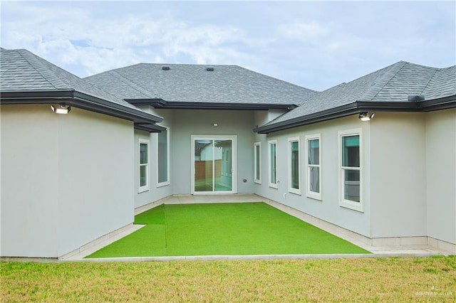 back of house featuring stucco siding, a shingled roof, a patio area, and a yard