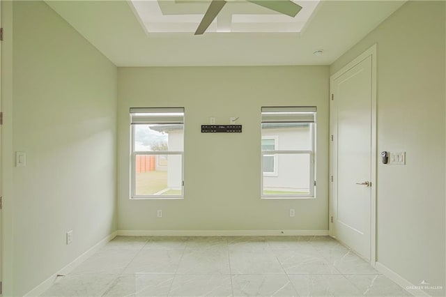 spare room featuring marble finish floor, baseboards, a tray ceiling, and ceiling fan