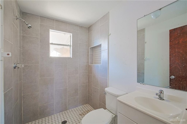 bathroom featuring vanity, toilet, and a tile shower