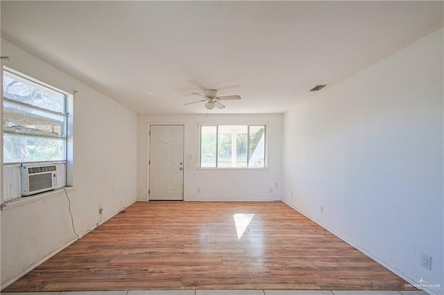 empty room featuring ceiling fan, cooling unit, and light hardwood / wood-style flooring