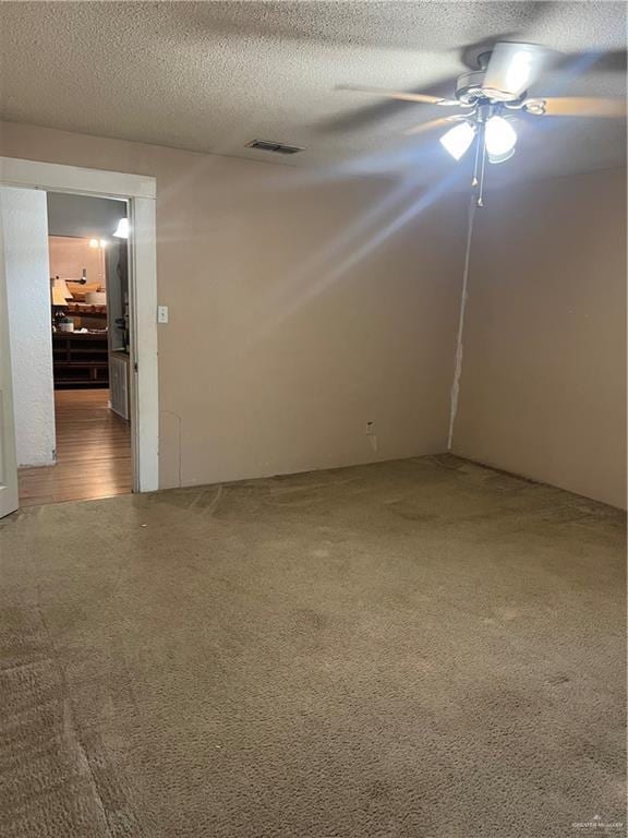 spare room featuring carpet flooring, ceiling fan, and a textured ceiling