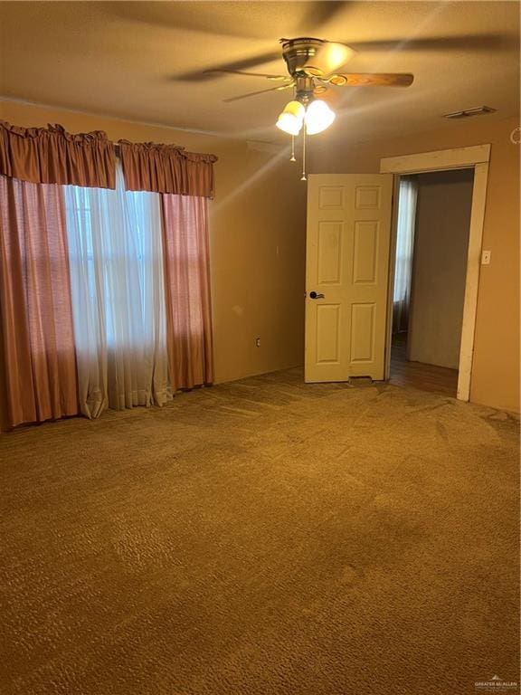 spare room with ceiling fan and carpet