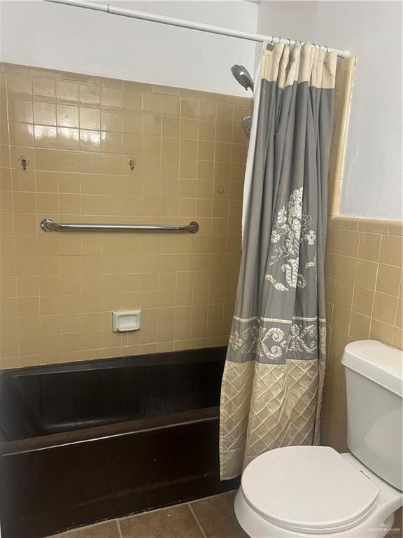 bathroom with tile patterned floors, shower / bath combination with curtain, toilet, and tile walls