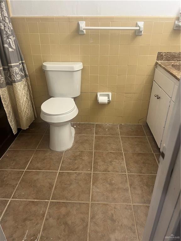 bathroom featuring tile patterned floors, vanity, toilet, and tile walls