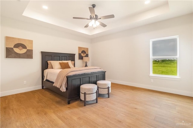 bedroom featuring recessed lighting, light wood finished floors, a raised ceiling, a ceiling fan, and baseboards